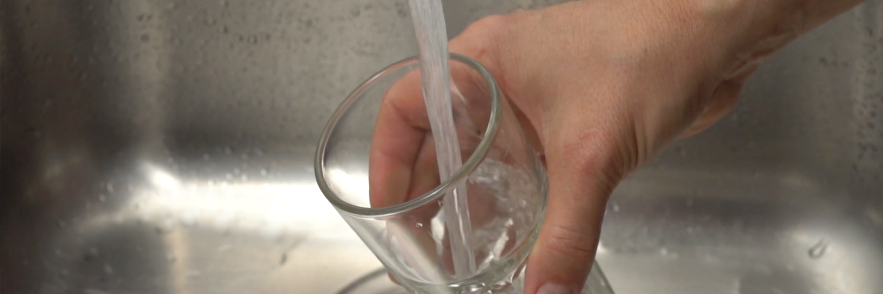A hand holding a glass under flowing water from tap | Credit: NOAA Research/Adobe Stock
