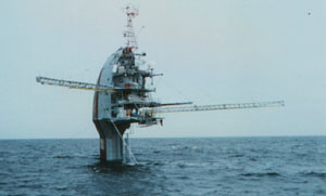 FLIP, a ship which can be partially submerged to form a fixed instrument platform, is shown in its buoy position supporting masts of instruments.