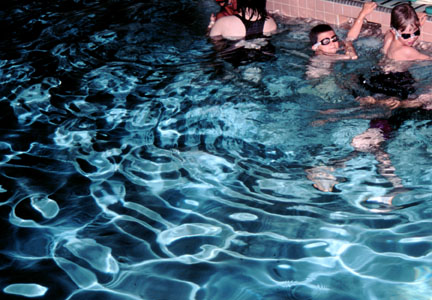 Reflections from a camera flash on the rough water of a swimming pool.